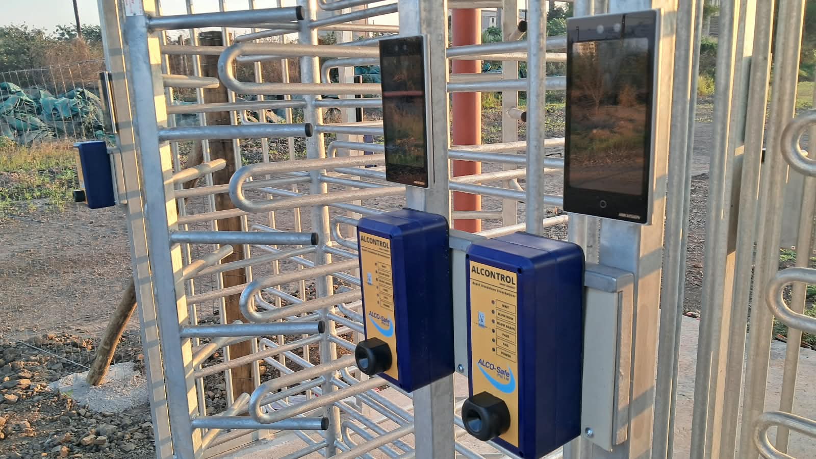 Two ALCONTROL breathalyzer access-control units with face-recognition readers mounted on full-height turnstiles at a client site